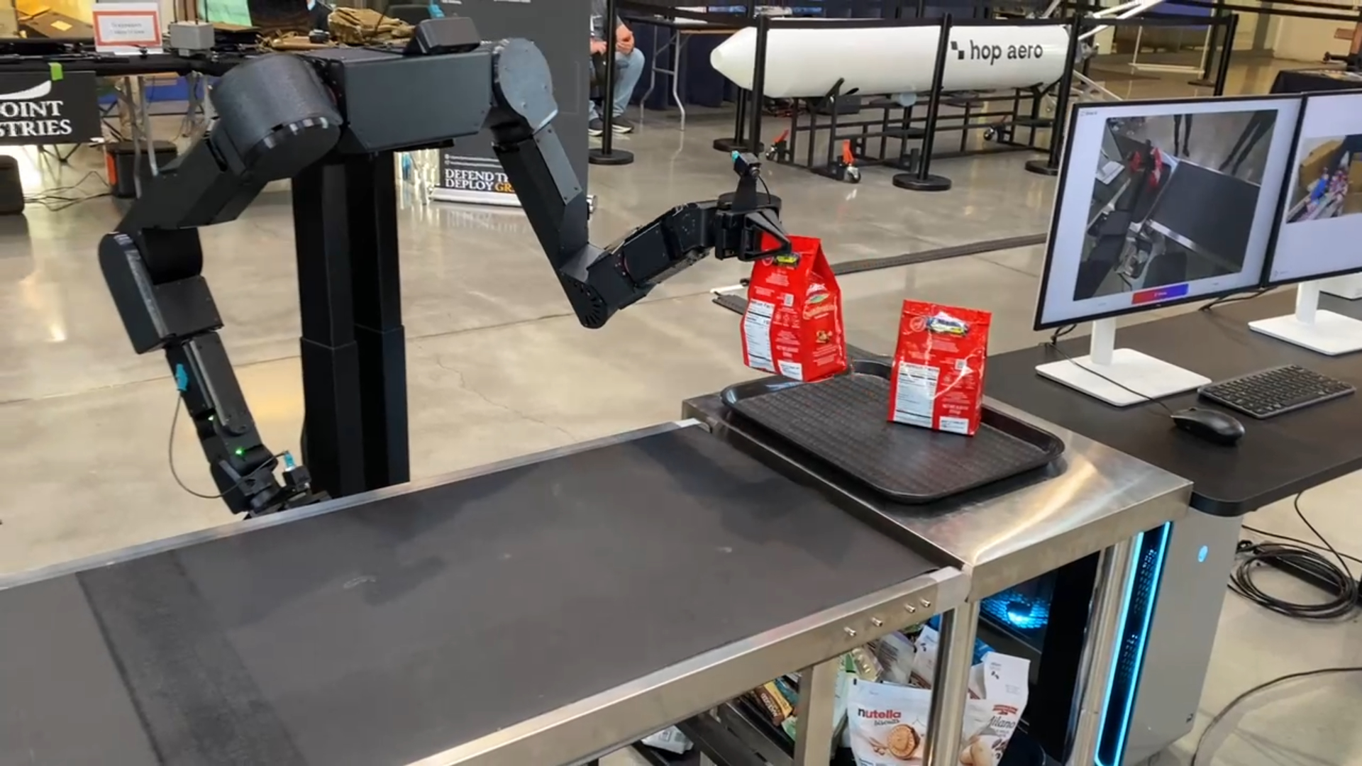 Shiraz AI robot handling packaged goods beside a conveyor at Demo Day